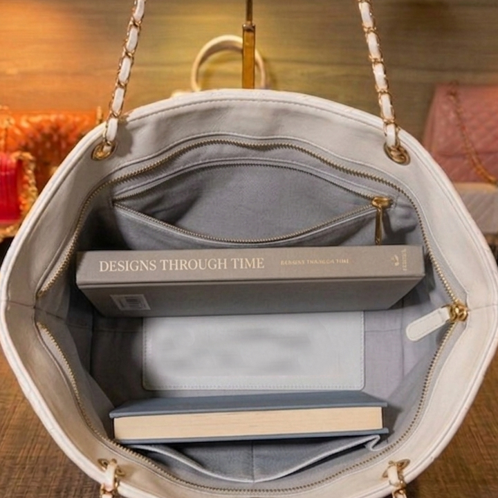 Inner view of white quilted tote bag showing black fabric lining with open pocket and zipper pocket