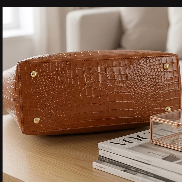 Bottom view of Vibe Totes brown crocodile leather tote bag highlighting protective metal feet studs