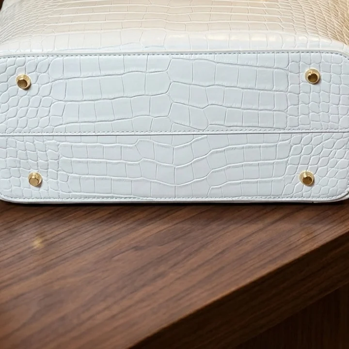 Bottom view of Vibe Totes white crocodile leather tote bag highlighting protective metal feet studs