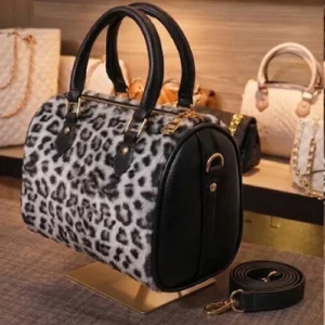 Front view of a white leopard print faux fur and black leather handbag by Vibe Totes, featuring a detachable strap for use as crossbody bags or shoulder bags.